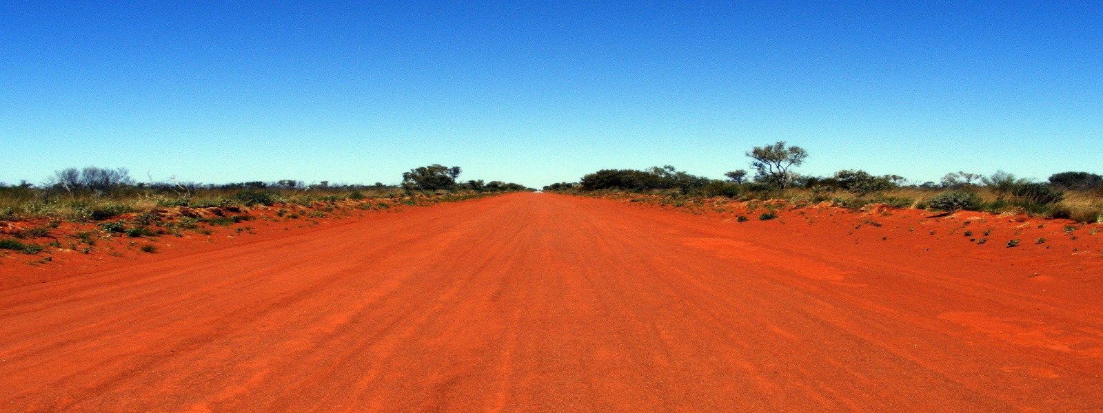 A red dirt road running through remote Australian scrub